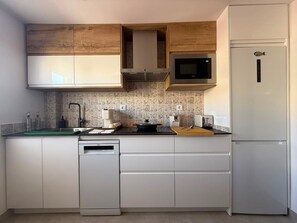 A compact kitchen with white cabinets, a microwave, a toaster, and a dishwasher.