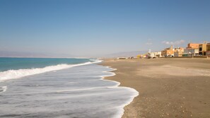 Una playa con vista despejada al océano y una hilera de edificios a lo largo de la costa.
