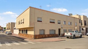 Un edificio residencial de varios pisos con fachada plana, múltiples ventanas y base de piedra.