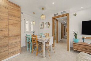A dining area with a wooden cabinet, a table set for four, and a television on a wooden stand.