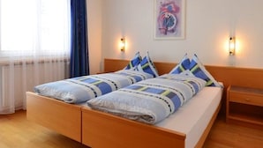 Een slaapkamer met een houten bed, twee bedlampen, een raam met gordijnen en een kunstwerk aan de muur.