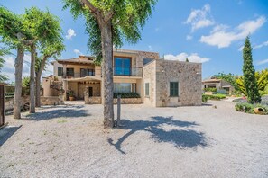 A two-story house with a stone facade, a balcony, and a gravel driveway. - 6-guest Stone Haven in Pollensa (Pollença)
