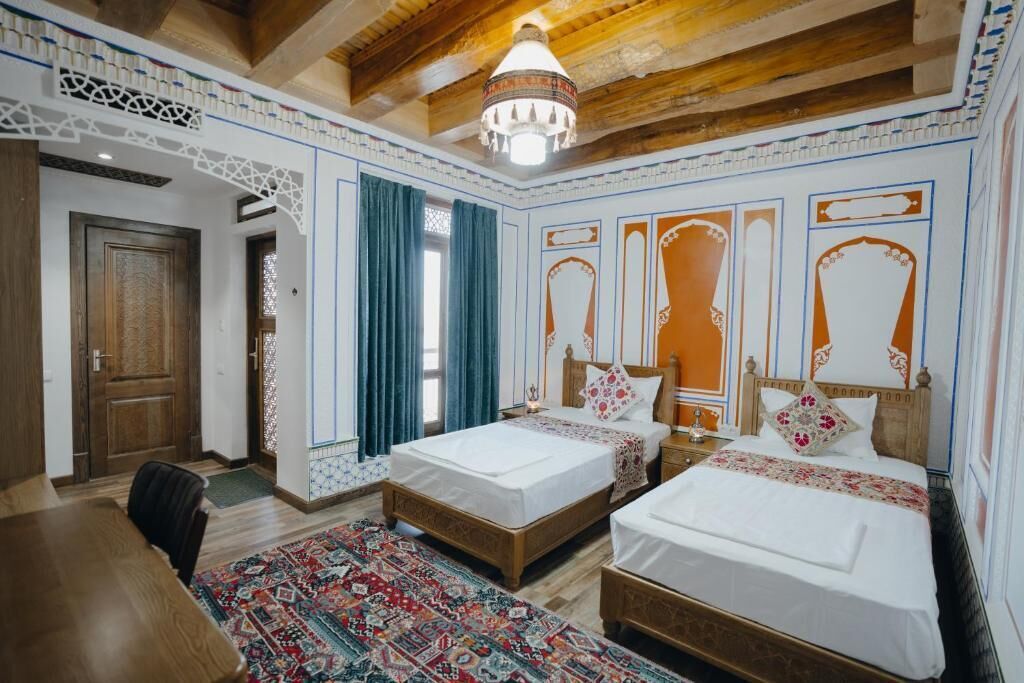Habitación tradicional con dos camas, techo de madera y paredes con diseños.