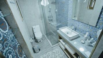 A bathroom with a glass shower enclosure, a white toilet, and a sink with a patterned countertop.