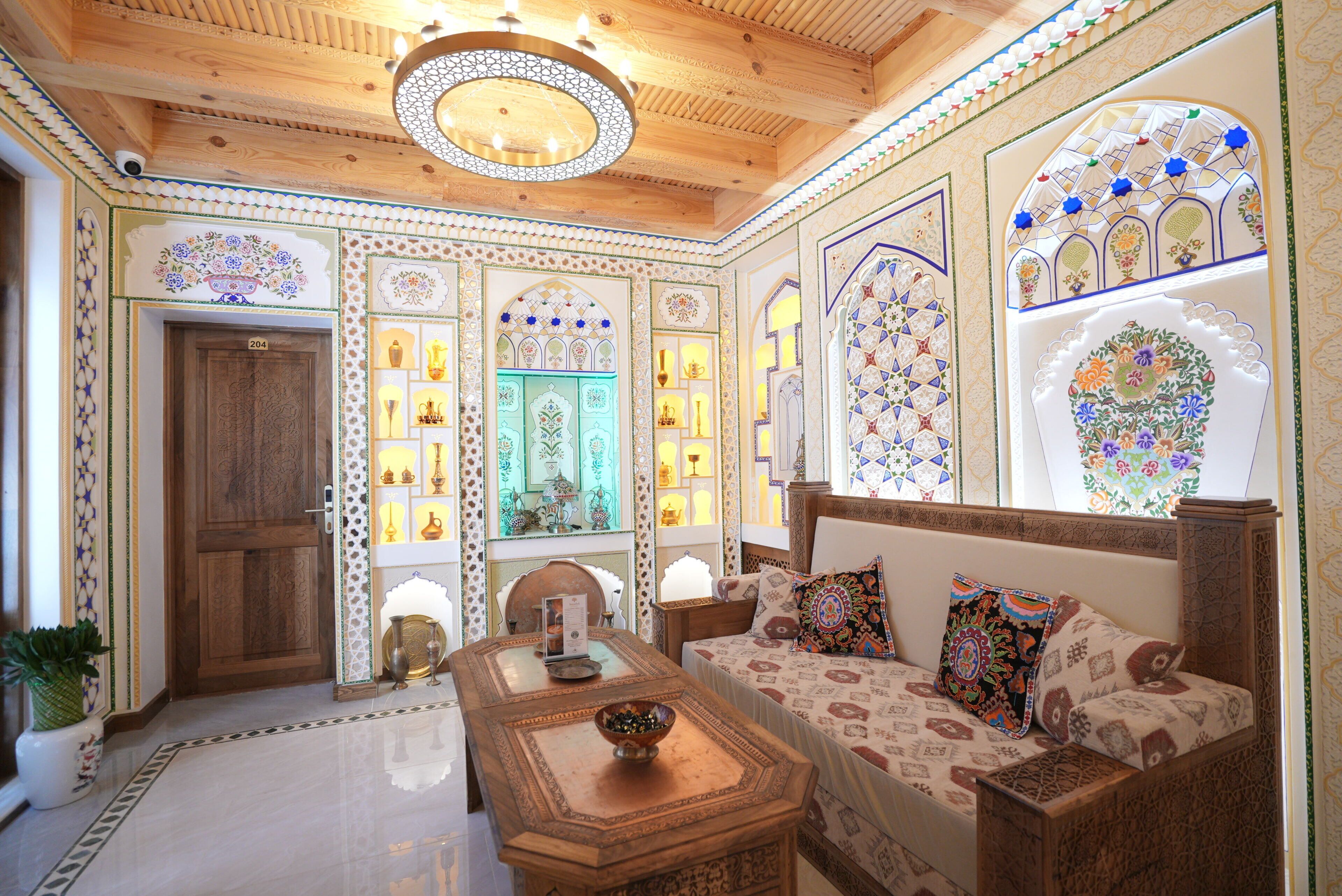 Un interior tradicional con techo de madera, decoraciones ornamentales en las paredes y una zona de estar con cojines.