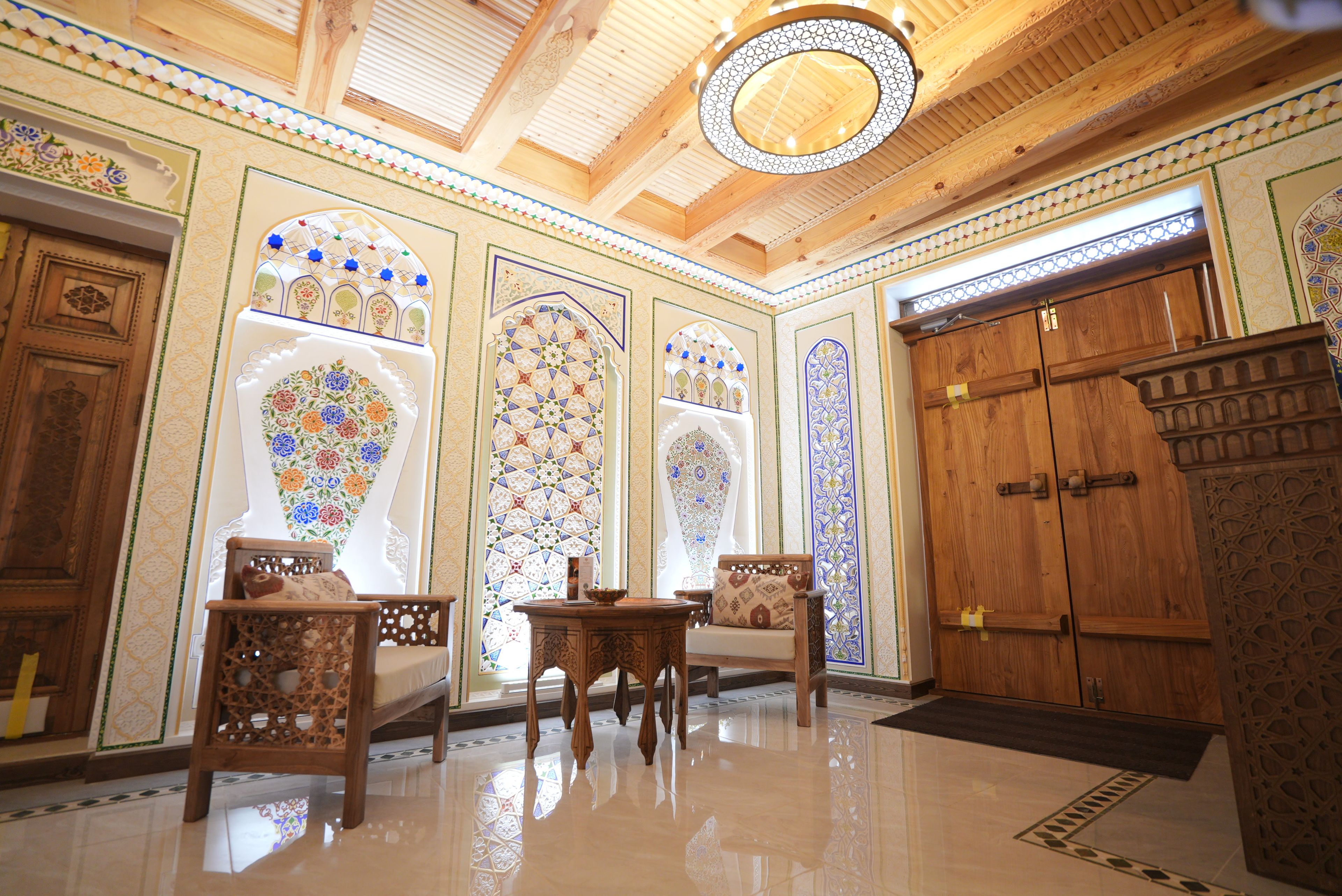 A room with ornate wooden doors, a chandelier, and a tiled floor.