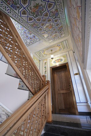 A staircase with ornate handrails and a wooden door with intricate carvings. - Imranbek Boutique Hotel (Bukhara)