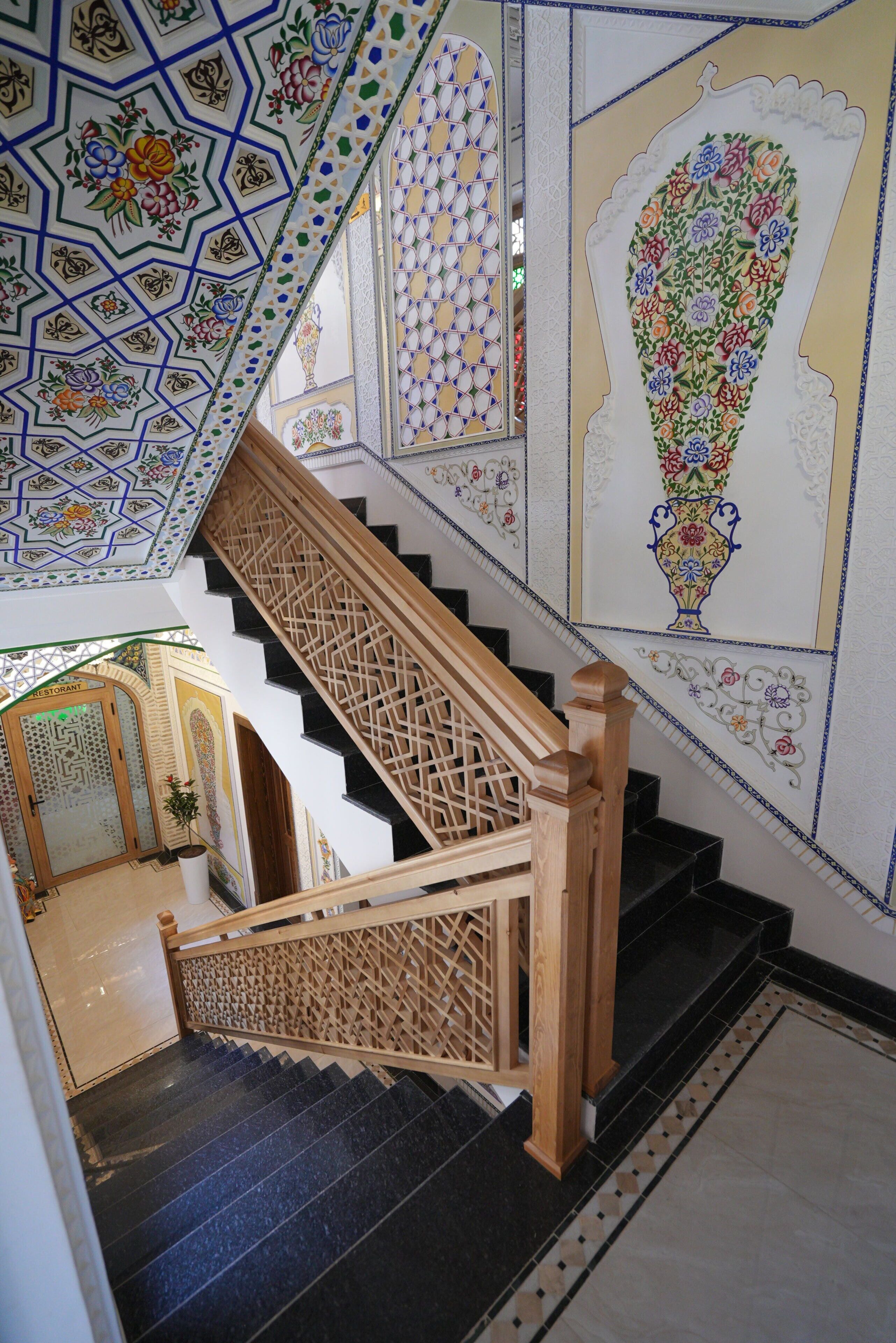 A staircase with intricate tile work on the walls and ceiling, leading to a room with a patterned door.