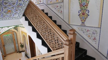 A staircase with intricate tile work on the walls and ceiling, leading to a room with a patterned door.