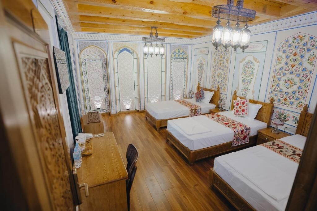 Una habitación tradicional con cuatro camas, suelo de madera y decoraciones ornamentales en las paredes.
