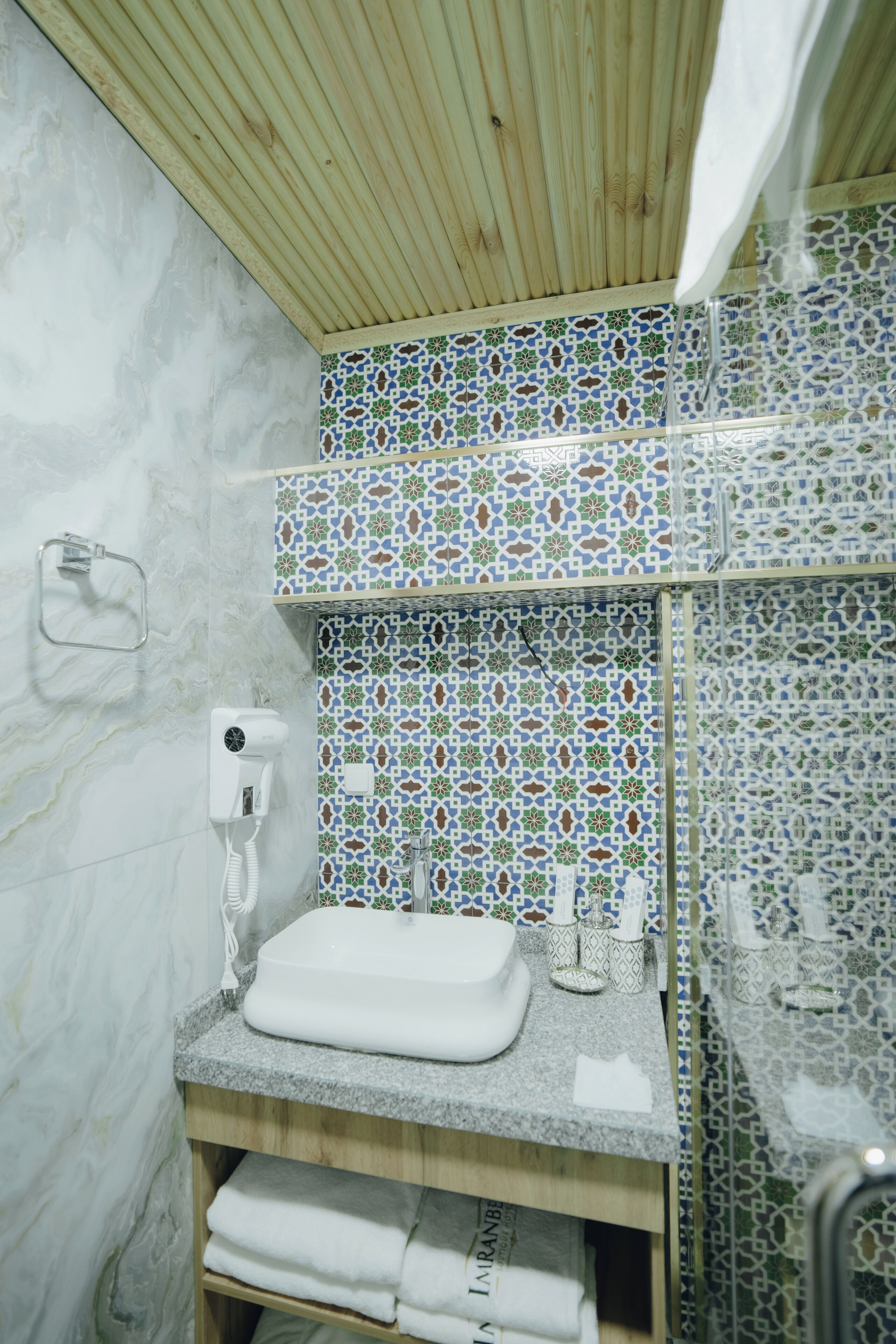 Un baño con lavamanos blanco, toallero y cortina de ducha.