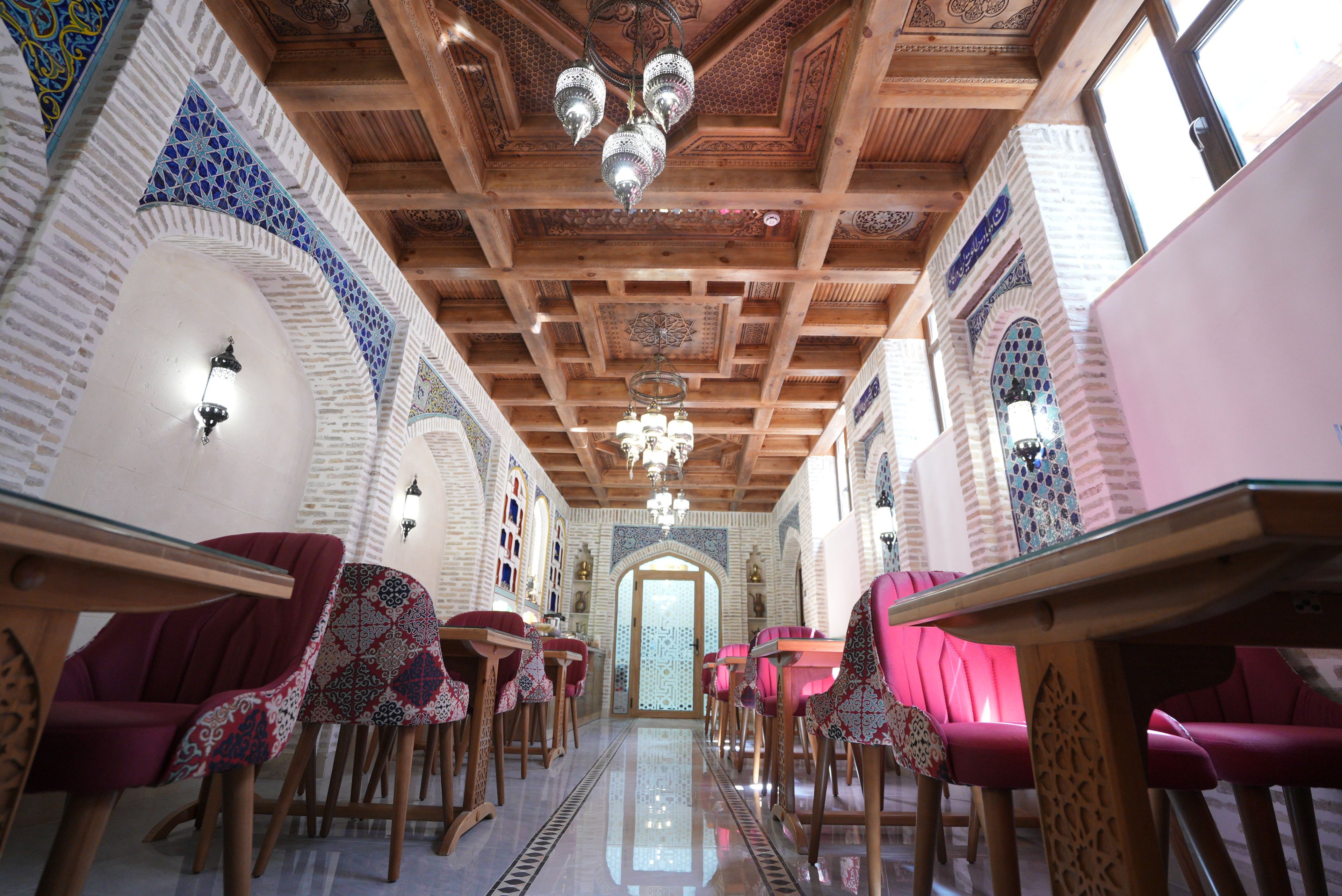 A room with a wooden ceiling, patterned walls, and a central chandelier.