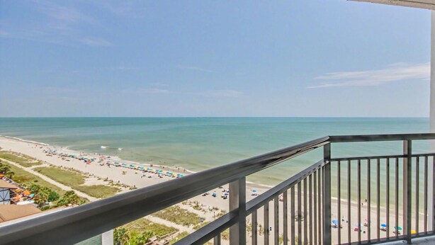 A balcony with a view of a beach and ocean.