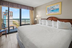 Ein Hotelzimmer mit einem großen Bett, einem Balkon mit Blick auf die Stadt und einem Bild an der Wand.