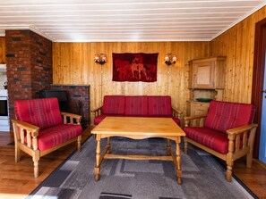 Una habitación acogedora con un banco de madera, dos sillones y una mesa.