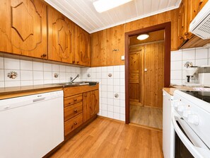 Eine Küche mit Holzausstattung, einem Geschirrspüler, einem Herd und einem Spülbecken.