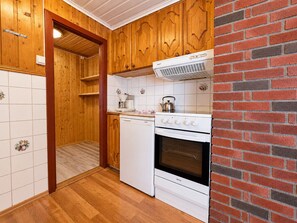 Una cocina con armarios de madera, estufa blanca y pared de ladrillo.
