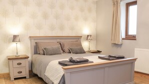 Ein Schlafzimmer mit Bett, Nachttischen, Lampen und einem Fenster.