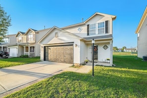 A two-story residential house with a garage, a front porch, and a well-maintained lawn. - Roadmap Lodging: 3BR Near Mill Race Park, Monthly (Columbus)