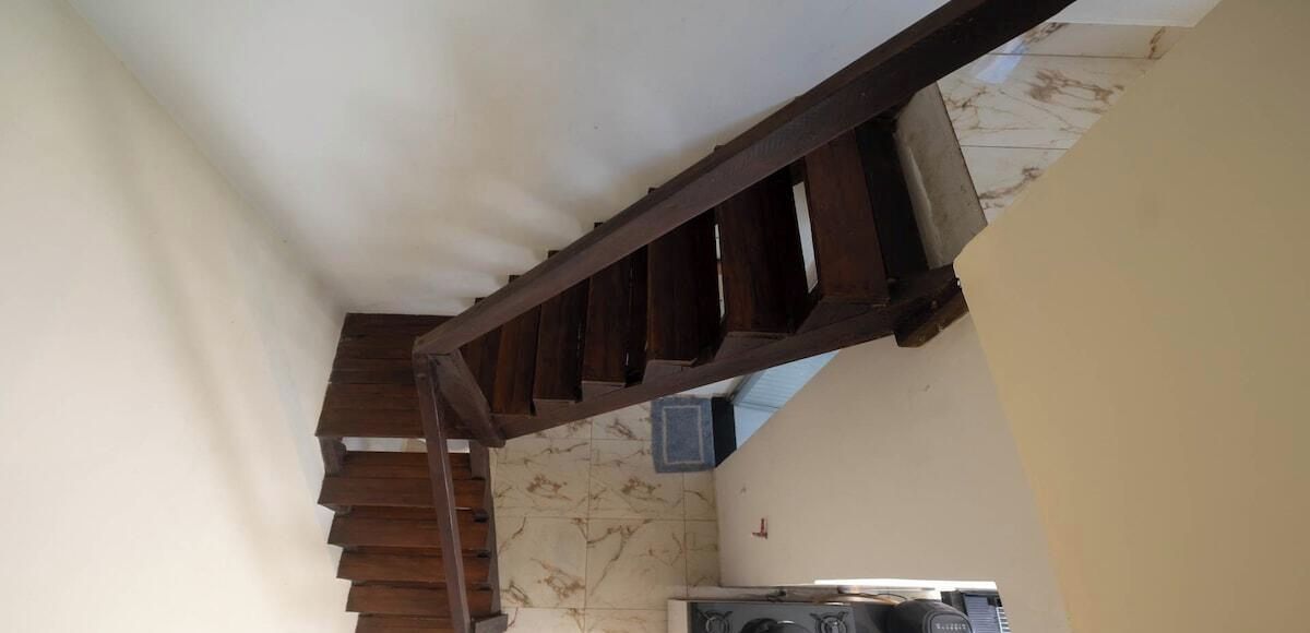A staircase with wooden railings leading to a room with a tiled floor and a stove.