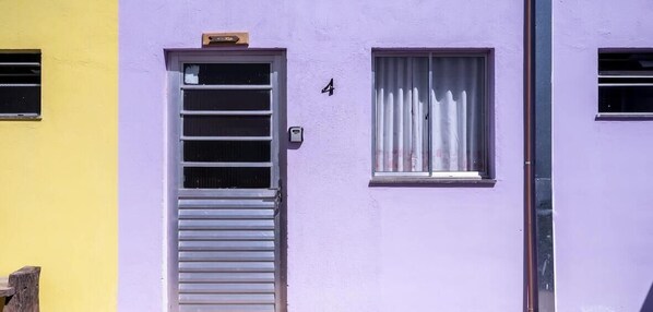 Un edifici amb una porta i una finestra, el número 4 a la porta, i una finestra petita amb cortines.