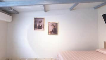 Ein Schlafzimmer mit einem Bett, einem an der Wand befestigten Fernseher und zwei gerahmten Bildern.