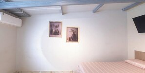 A bedroom with a bed, a wall-mounted TV, and two framed pictures.