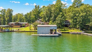 A lakeside property with a dock, a small shed, and a house with a deck.