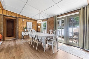 A dining area with a wooden interior, a chandelier, and a view through glass doors. - New! 2 home property on Lake Martin, sleeps 12! (Dadeville)