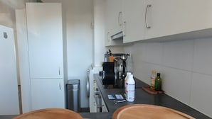 A compact kitchen with white cabinets, a stainless steel sink, and a coffee machine. - Apartment 'ViewRoyal' with Sea View, Balcony and Wi-Fi (Katwijk)