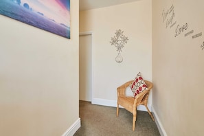 A hallway with a wicker chair, a door, and decorative wall art including a flower and inspirational phrases. - Host Stay Norwood Street (Scarborough)