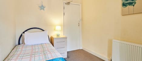 A bedroom with a bed, bedside table, lamp, and a door.