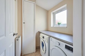 A laundry room with a washing machine, dryer, and a window with a plant. - Host Stay Norwood Street (Scarborough)