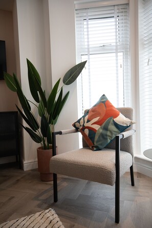 A room with a chair, a potted plant, and a window with blinds. - Pinot Perch - With Free Underground Parking (Whitby)