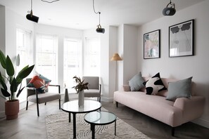 A modern living room with a sofa, two chairs, a coffee table, and a floor lamp. - Pinot Perch - With Free Underground Parking (Whitby)
