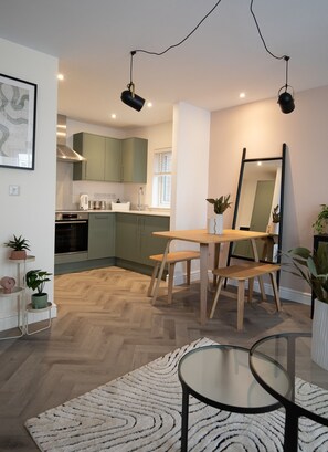 A modern kitchen with green cabinets, a dining table with benches, and pendant lighting. - Pinot Perch - With Free Underground Parking (Whitby)