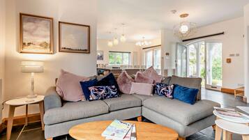 A modern living room with a sectional sofa, a coffee table, and a dining area in the background.