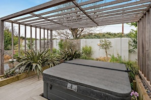 Un jacuzzi bajo una pérgola de madera con vistas al jardín.
