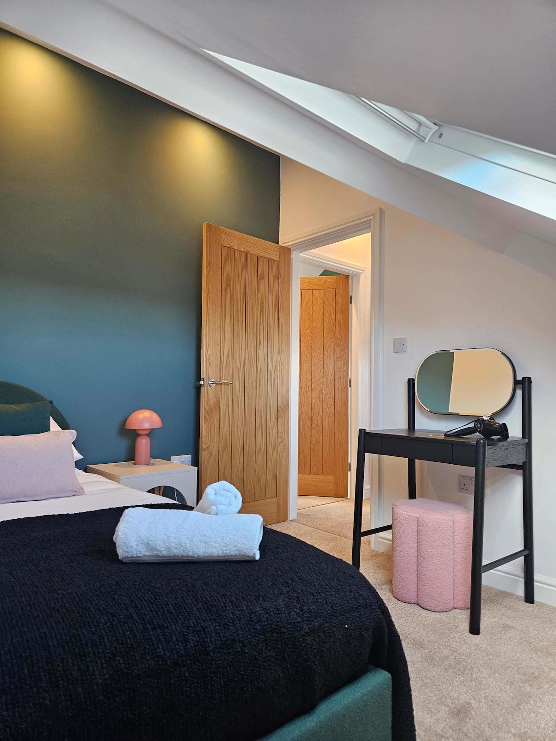 Ein Schlafzimmer mit einem Bett, einem Nachttisch, einem Spiegel und einer Tür zu einem anderen Raum.