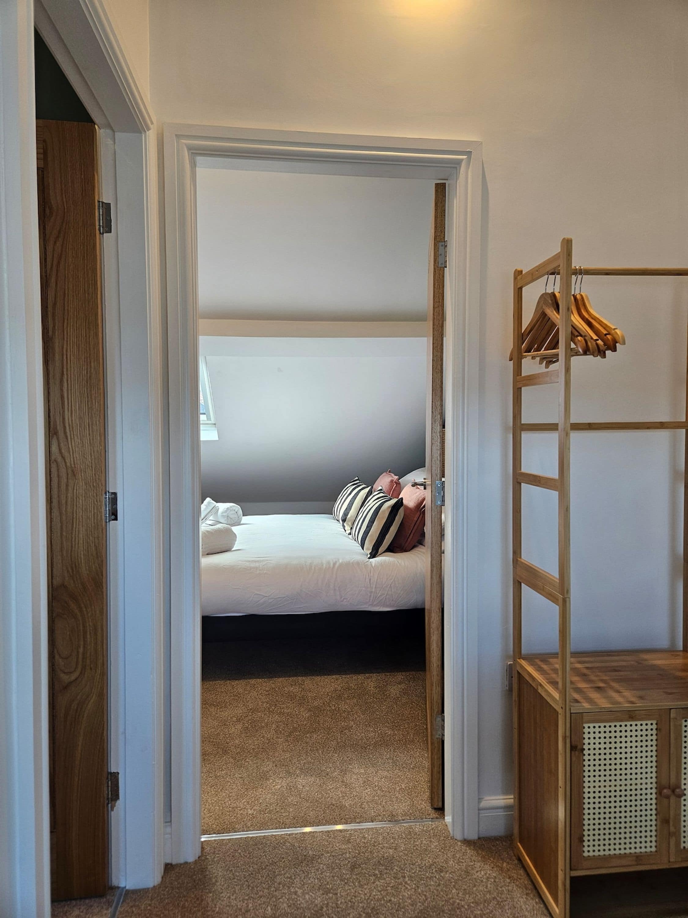 A bedroom with a bunk bed, a wooden wardrobe, and a clothing rack.