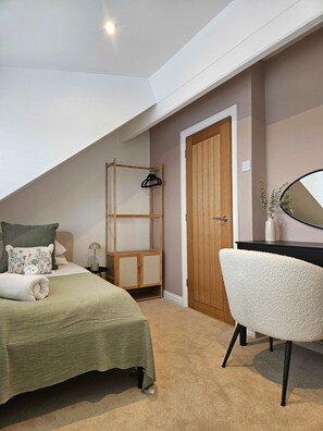 Una camera da letto con un letto, un armadio in legno, una scrivania con uno specchio e una sedia.
