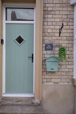 A teal door with a small window, a mailbox, and a sign reading 'Sea Renity' on a brick wall. - Sea Renity - Whitby (Whitby)