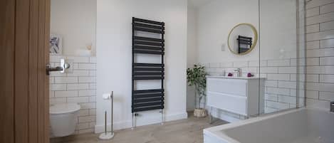 A modern bathroom with a toilet, a black towel rack, a mirror, and a white sink.