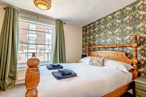 Ein Schlafzimmer mit einem großen Fenster, einem Bett mit Holzschrankgitter und einer Wand mit Muster-Tapete.