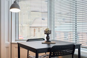 Spisebord med lysestage i midten, sorte stole og en hængende lampe.
