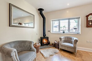 A cozy room with a fireplace, two armchairs, a large mirror, and a window with a view. - Host Stay Thornbank (Chichester)