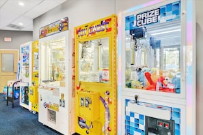 Uma fileira de máquinas de jogos com etiquetas de prêmios, incluindo 'Toy Chest' e 'Prize Cube'.