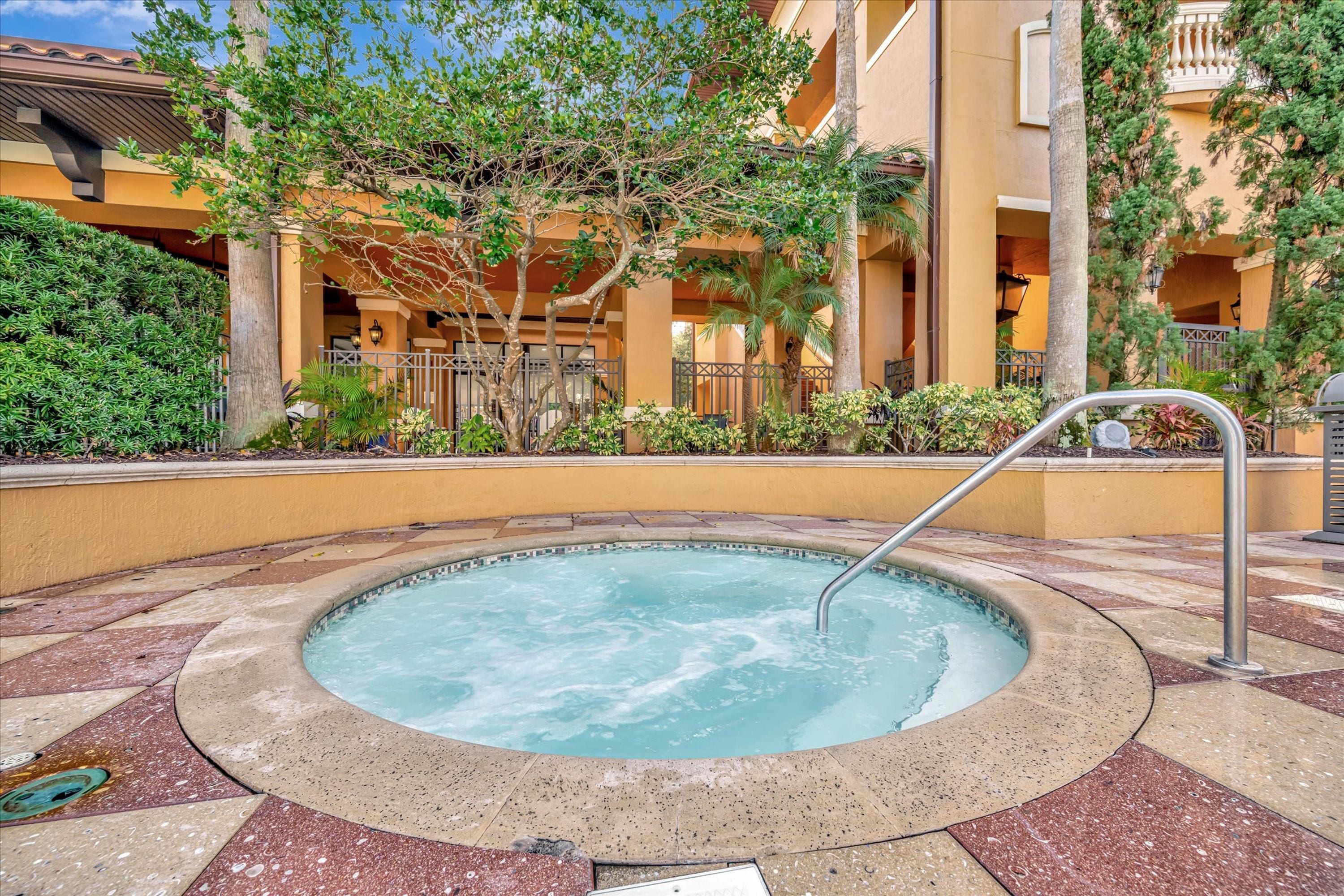Uma banheira de hidromassagem cercada por um terraço revestido com azulejos e um edifício ao fundo.