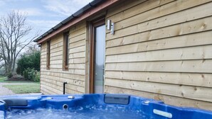 A wooden house with a hot tub in front. - Gardener's Lodge (Nantwich)