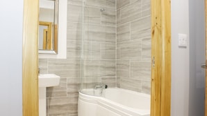 A bathroom with a bathtub, a sink, and a shower. - Gardener's Lodge (Nantwich)